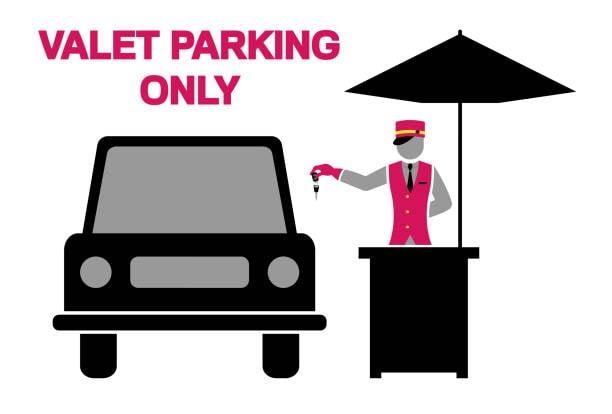 A valet attendant in a red uniform holds car keys at a parking stand beside a black car, representing valet parking services Dubai for secure and hassle-free parking.